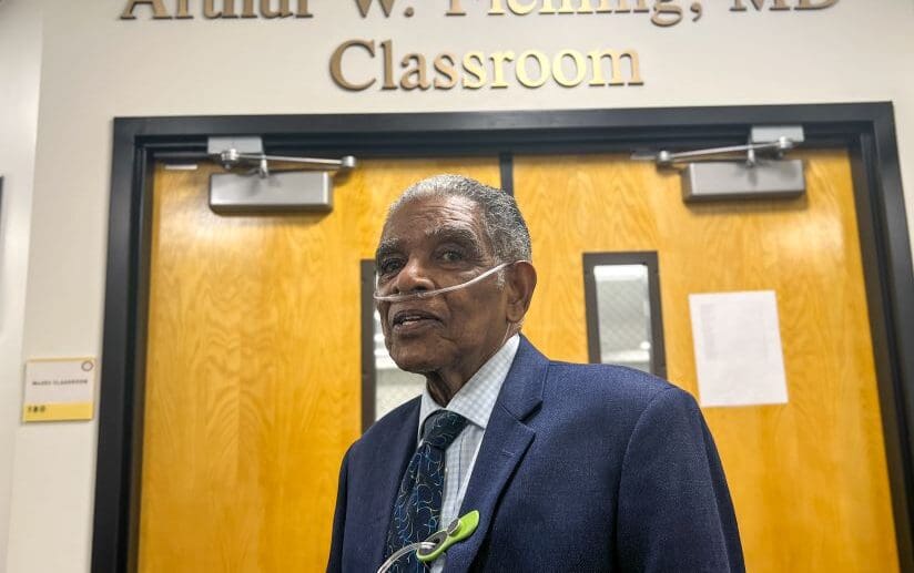 Dr. Arthur W. Fleming poses in front of the classroom named after him
